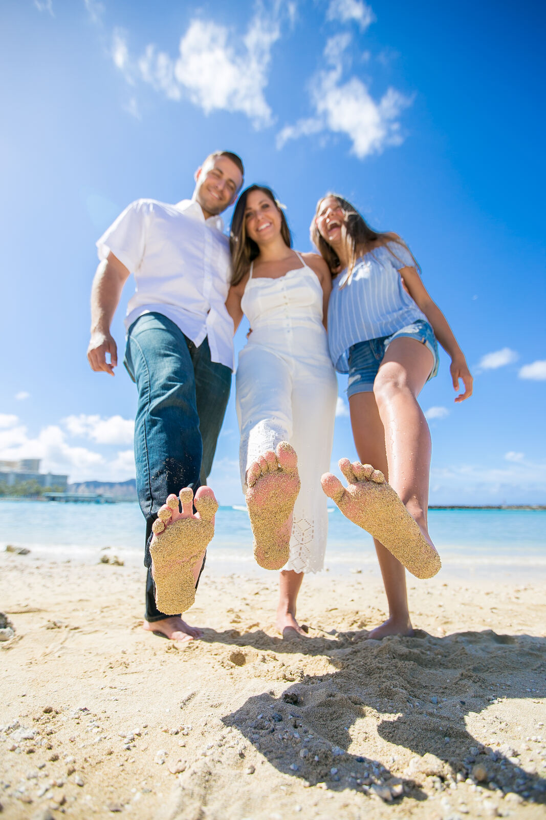 Sandy bare feet of a family of three on Waikiki Beach