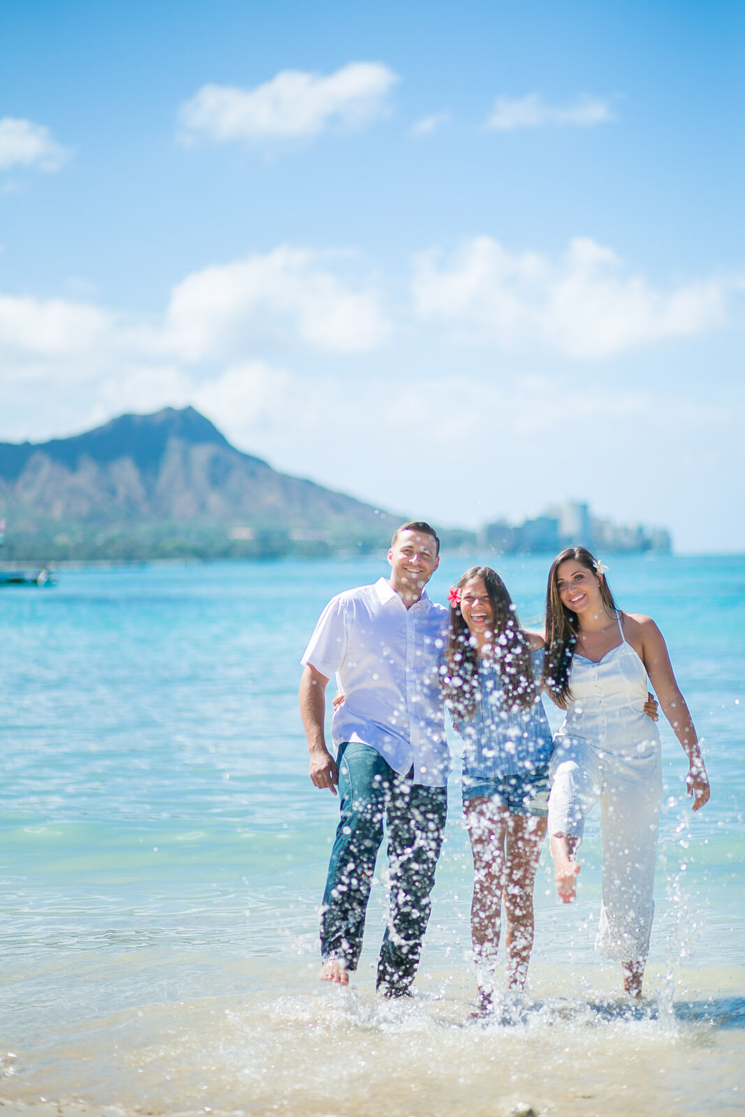 Family walking through the shallows with Diamond Head behind them