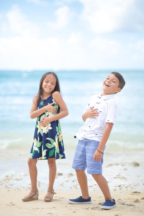 Brother and sister laughing together on the beach