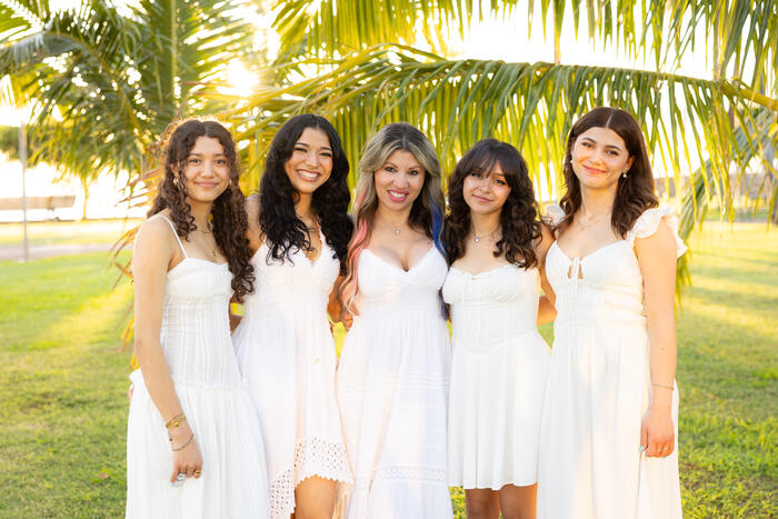 Mother and daughters posing under a palm tree at sunset